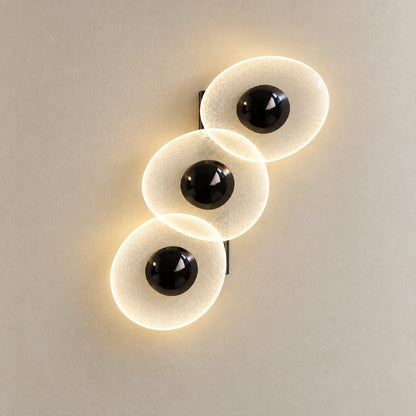Triple oval illuminated wall art on a warm studio wall