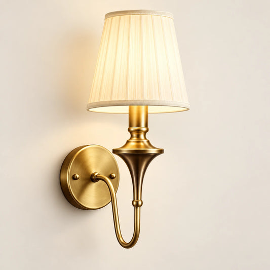 Single arm tapered shade wall sconce with curved brass-tone arm