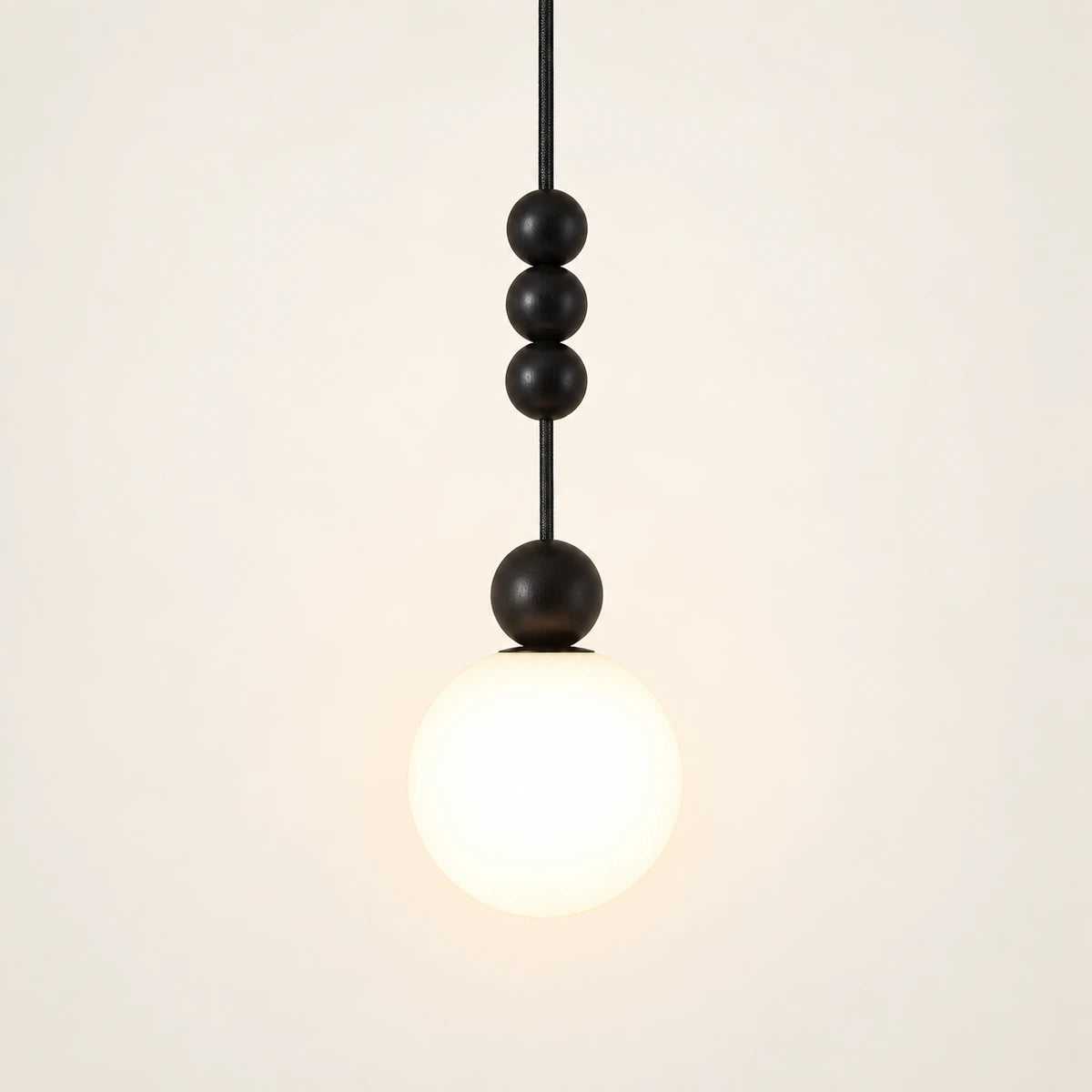 Decorative black bead and white globe pendant on a warm studio background