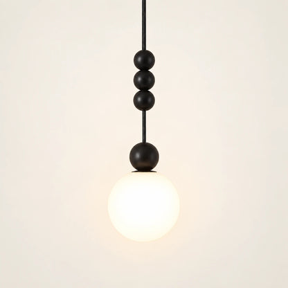 Decorative black bead and white globe pendant on a warm studio background