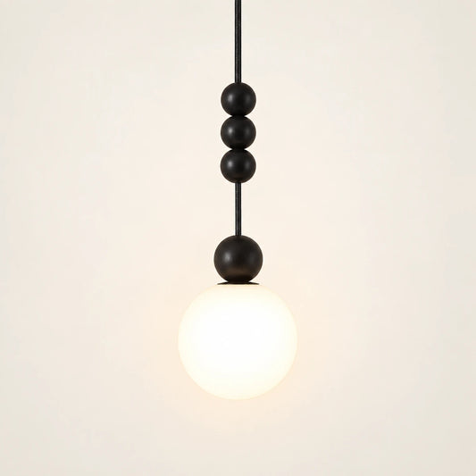 Decorative black bead and white globe pendant on a warm studio background