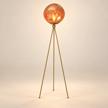Amber glass globe floor lamp on three slender gold-tone legs