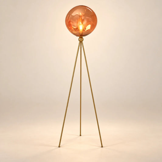 Amber glass globe floor lamp on three slender gold-tone legs