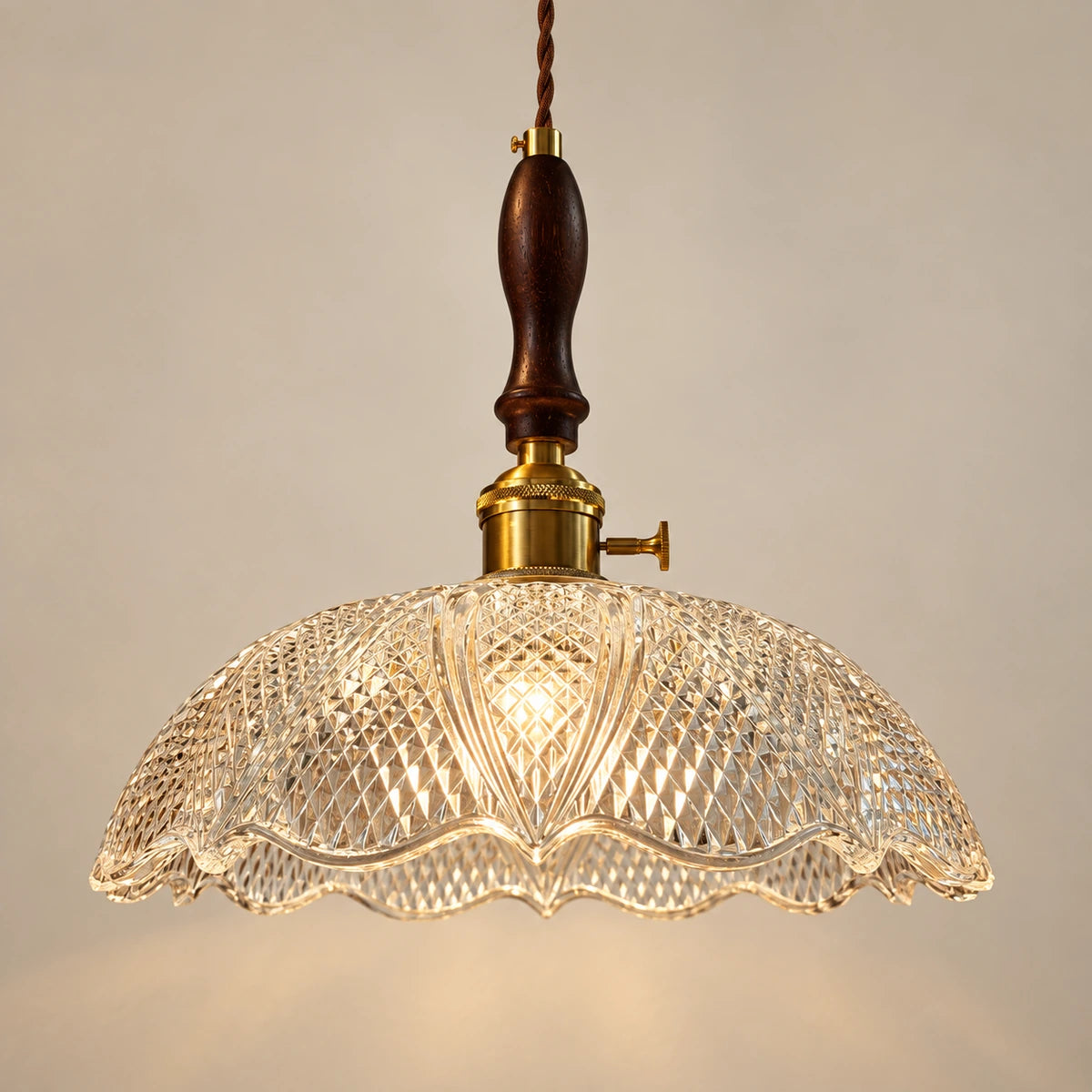 Diamond-cut clear glass dome pendant with dark wood spindle and warm metal fitting