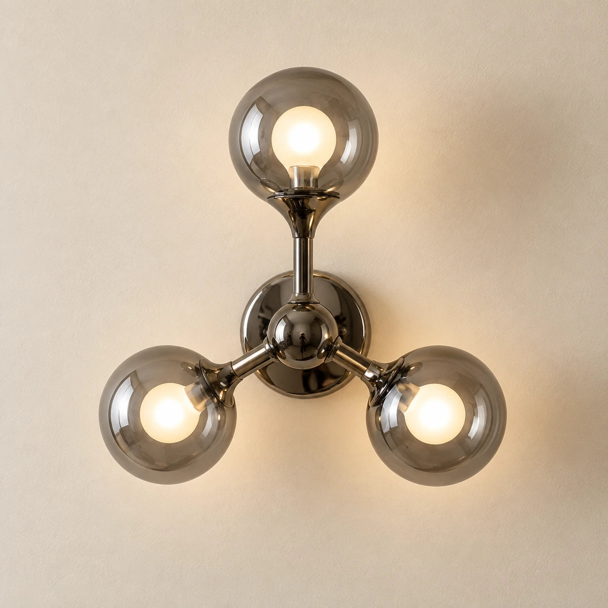 Three smoke-glass globe wall sconce with connected dark metal arms