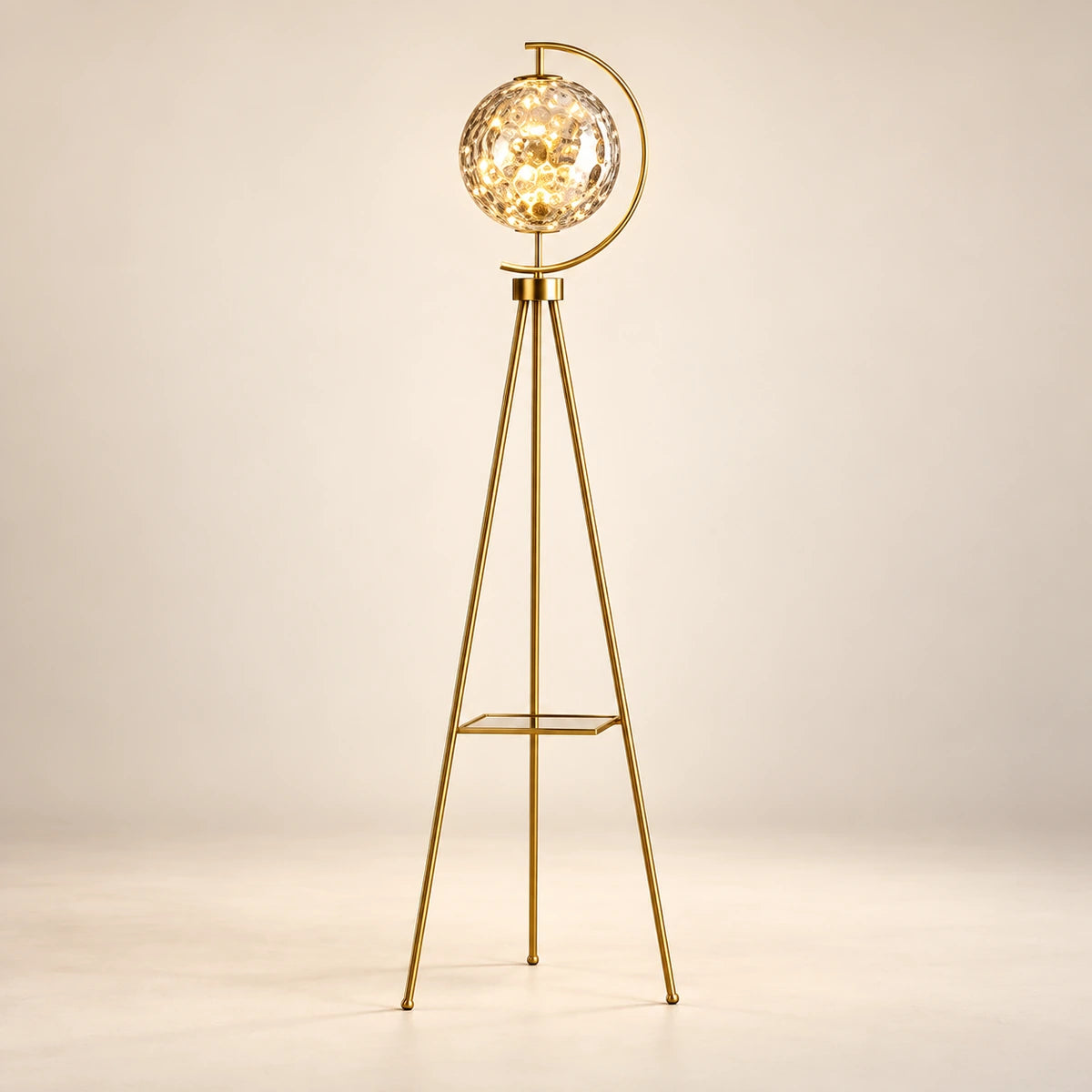 Gold-tone tripod floor lamp with a patterned glass globe and flat shelf