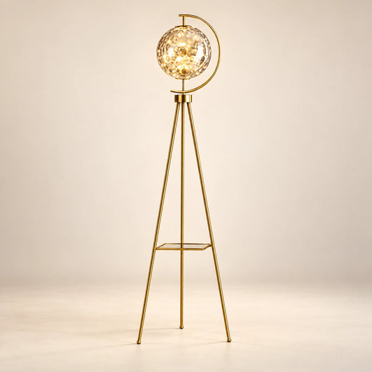 Gold-tone tripod floor lamp with a patterned glass globe and flat shelf