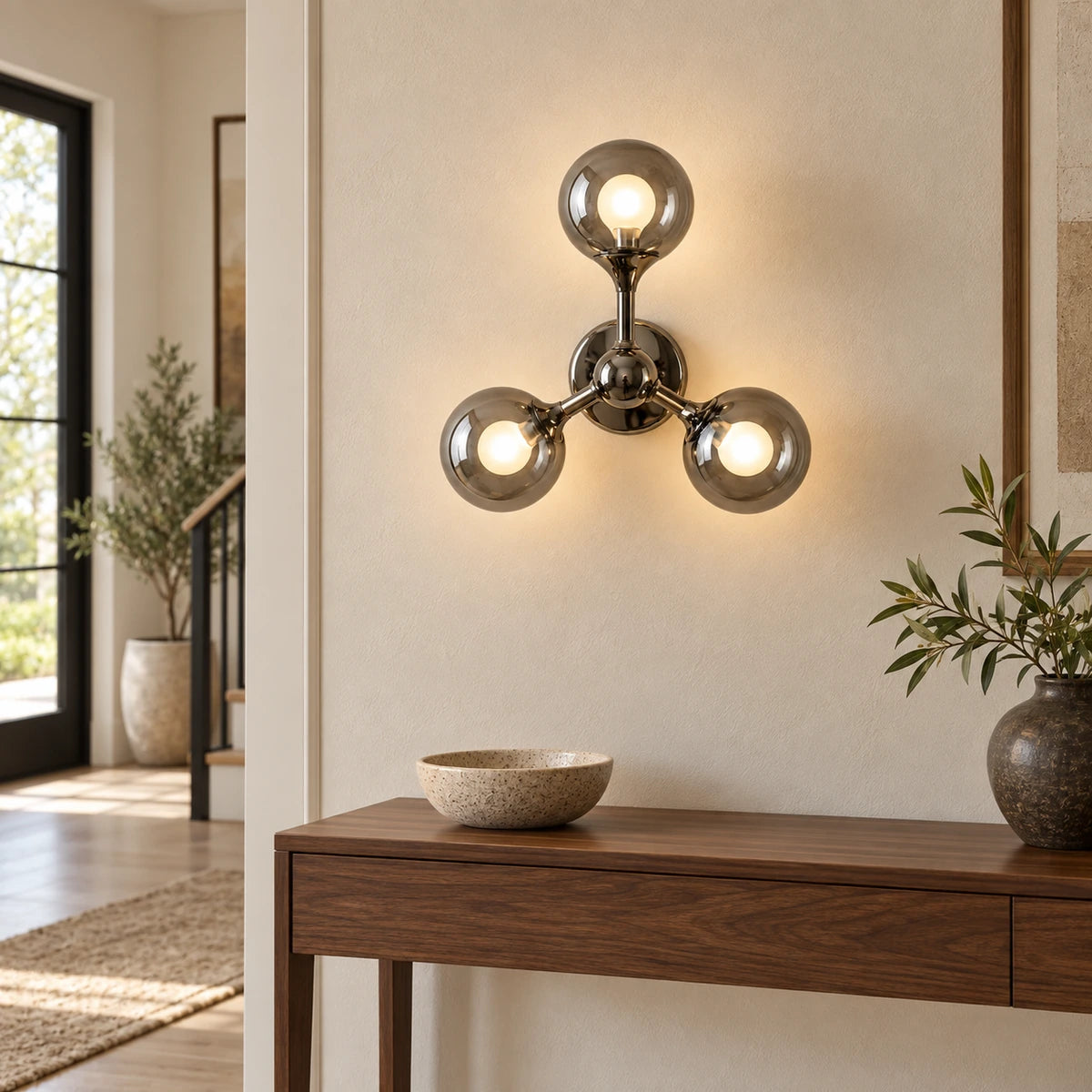 Three-globe smoke-glass wall sconce above an entry console