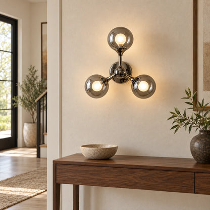 Three-globe smoke-glass wall sconce above an entry console
