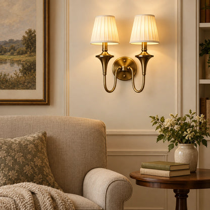 Double arm tapered shade wall sconce illuminating an indoor reading corner