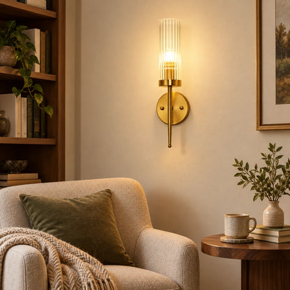 Ribbed glass cylinder wall sconce illuminating an indoor reading corner