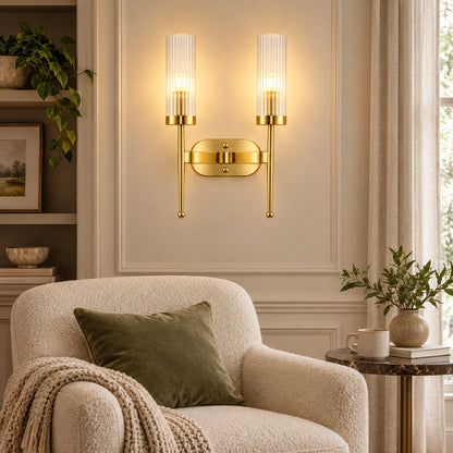 Twin ribbed glass cylinder wall sconce illuminating an indoor reading corner