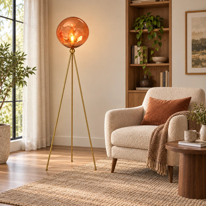 Amber-globe tripod floor lamp at scale beside a reading chair