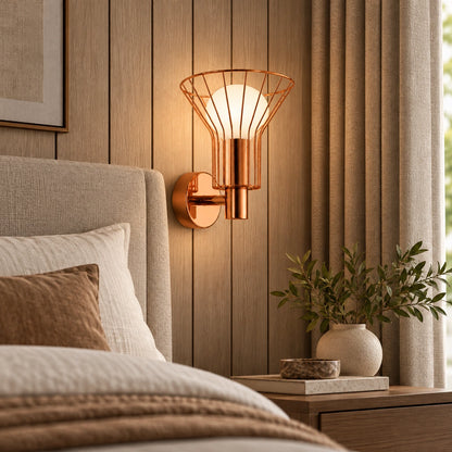 Rose-gold wire-cage globe wall light beside a bed