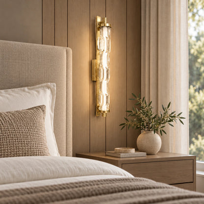 Sculpted clear-glass gold wall light beside a bed