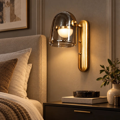 Smoked glass and brushed-gold wall light beside a bed