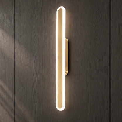 Square product view of the Luma Loop vertical LED wall light illuminated on a dark wood wall