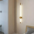 Gold linear LED wall light beside a bed