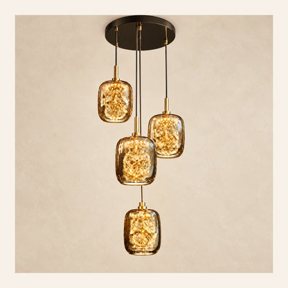 Four-light amber glass cluster pendant on a warm studio background