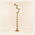Sculptural gold vine floor lamp on a warm studio background