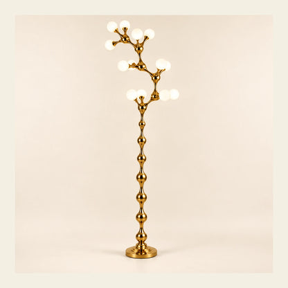 Sculptural gold vine floor lamp on a warm studio background