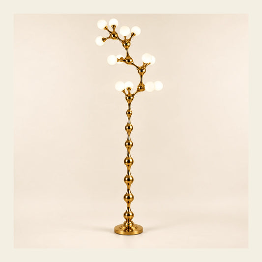 Sculptural gold vine floor lamp on a warm studio background